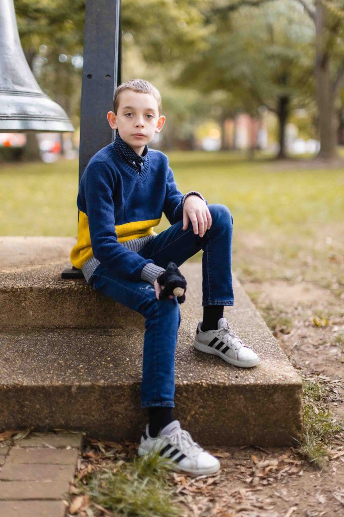 A boy sitting on steps next to a bell in Downtown Annapolis.