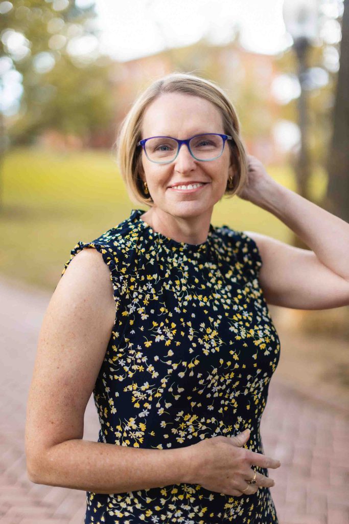 A woman in glasses is posing for a portrait in Downtown Annapolis.