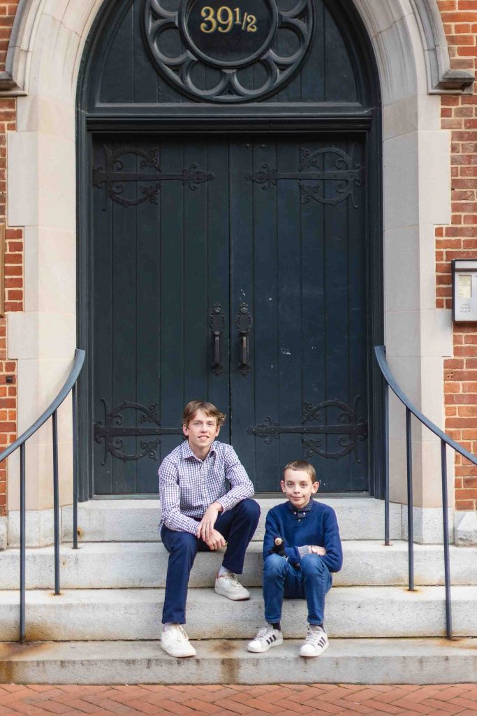 Description: Two boys sitting on the steps of a brick building in downtown Annapolis, capturing family portraits.