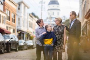 A family poses for portraits in Downtown Annapolis, with a clock tower in the background.