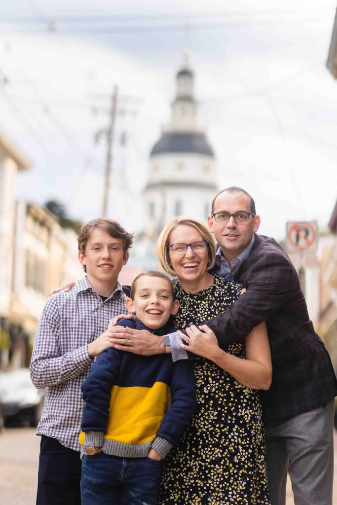 A family is posing for a portrait in front of a clock tower in downtown Annapolis.