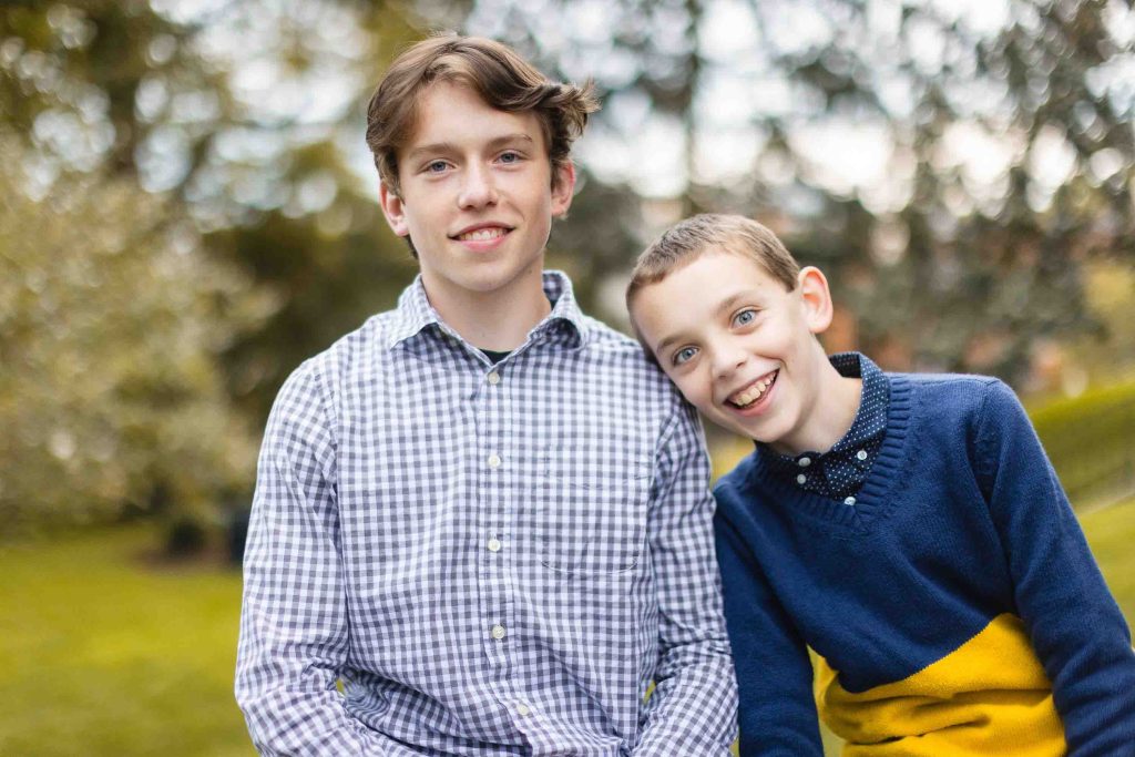 Two boys posing for a family photo in a park.