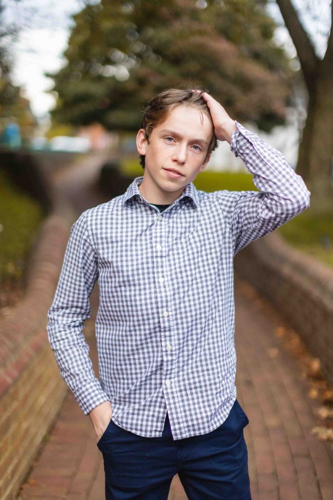 A young man in a plaid shirt standing on a brick walkway in downtown Annapolis.