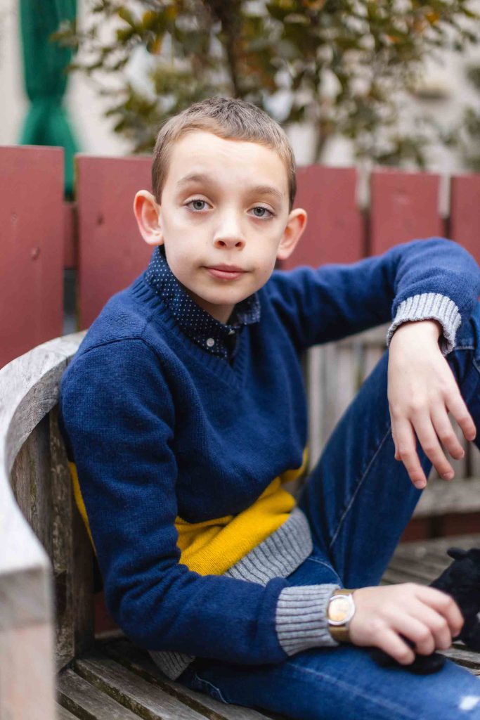A family portrait in downtown Annapolis, with a boy sitting on a bench wearing a blue sweater and jeans.