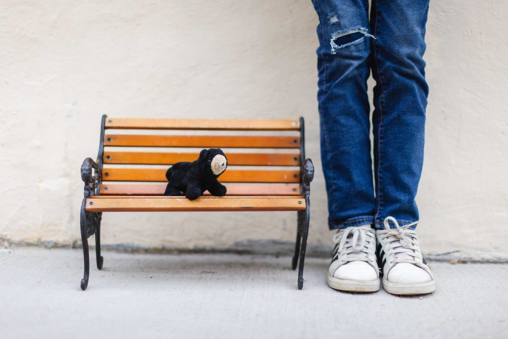 A black teddy bear sitting on a wooden bench in Downtown Annapolis.