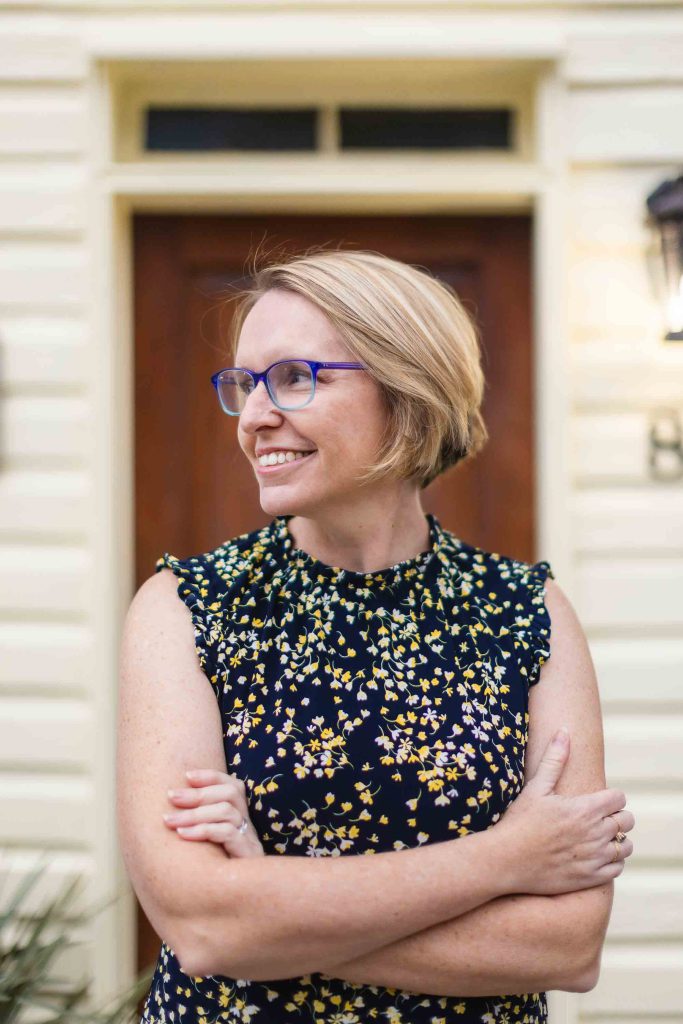 A woman in glasses standing in front of a downtown Annapolis house.