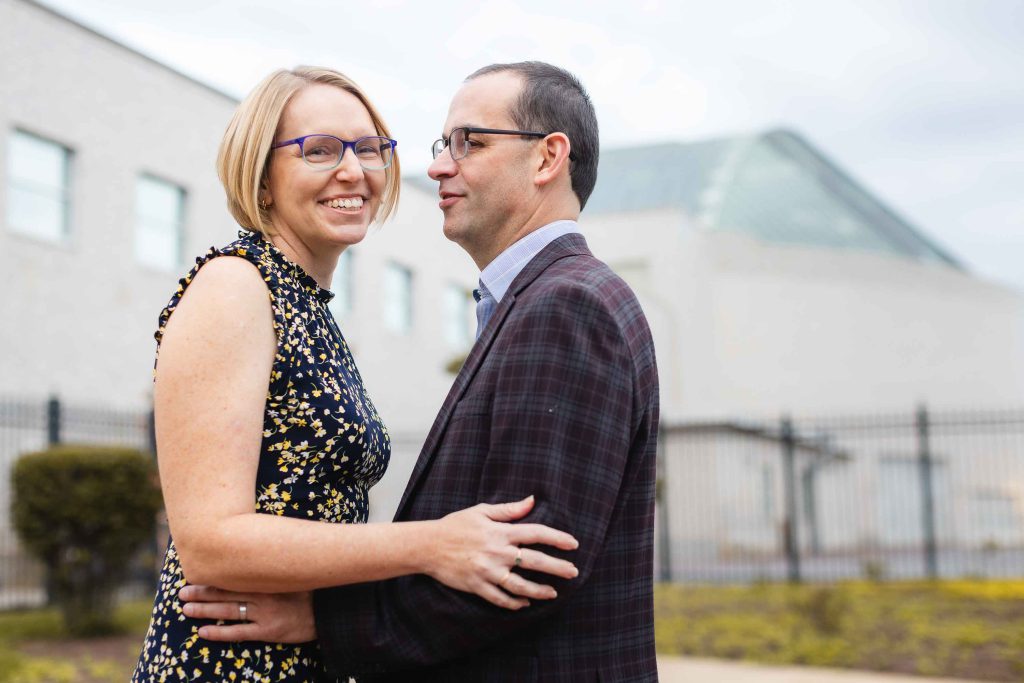 A man and woman are embracing in front of a building in Downtown Annapolis, creating a beautiful portrait that portrays the essence of family.