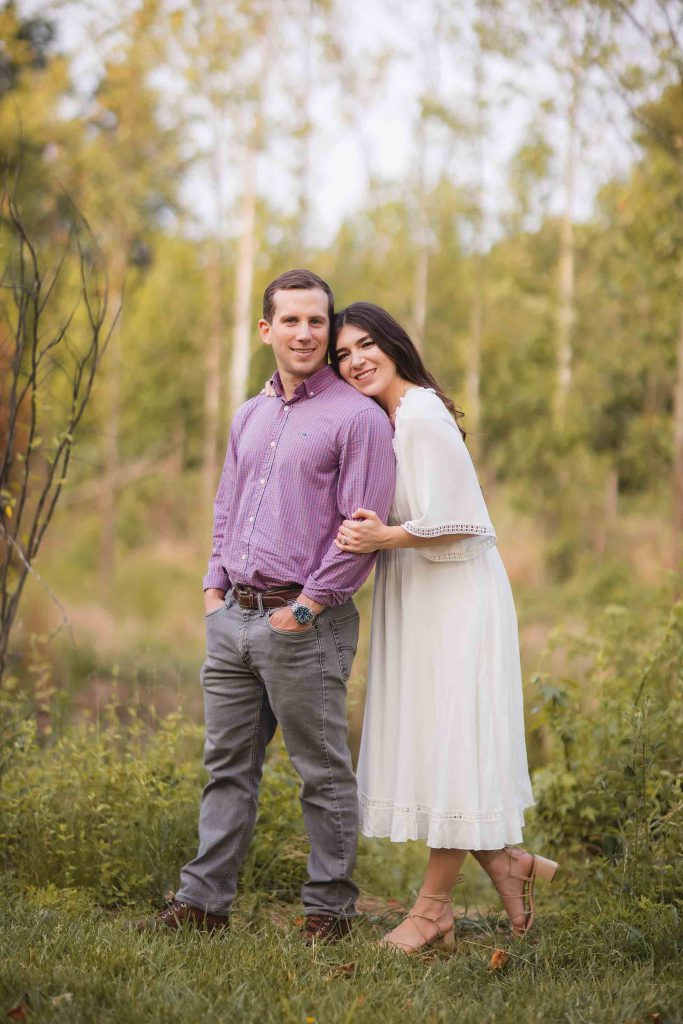 An engaged couple posing for a photo in the enchanting Patuxent Research Refuge, bathed in the warm hues of a sunset.