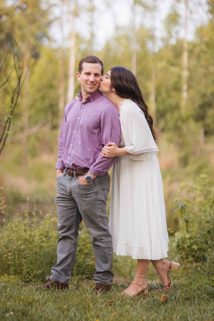 A couple kisses in the woods during their engagement session at Patuxent Research Refuge in Maryland, capturing stunning engagement photos.