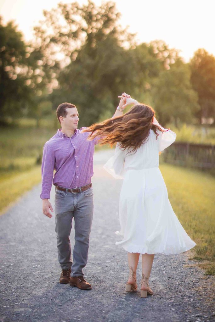 A couple is walking down a path at the Patuxent Research Refuge in Maryland with their hair blowing in the wind during sunset.