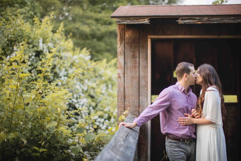 A couple kisses at sunset in front of a wooden shed at Patuxent Research Refuge in Maryland.