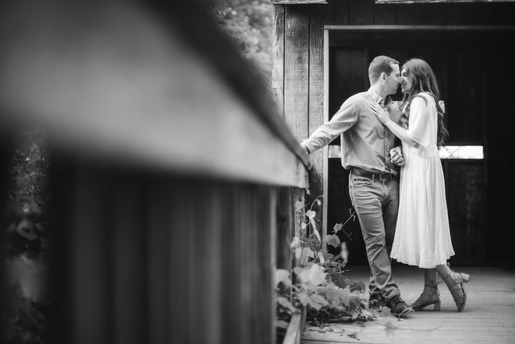 A black and white photo of a couple kissing on a wooden bridge at Patuxent Research Refuge in Maryland. [Engagement Photos]
