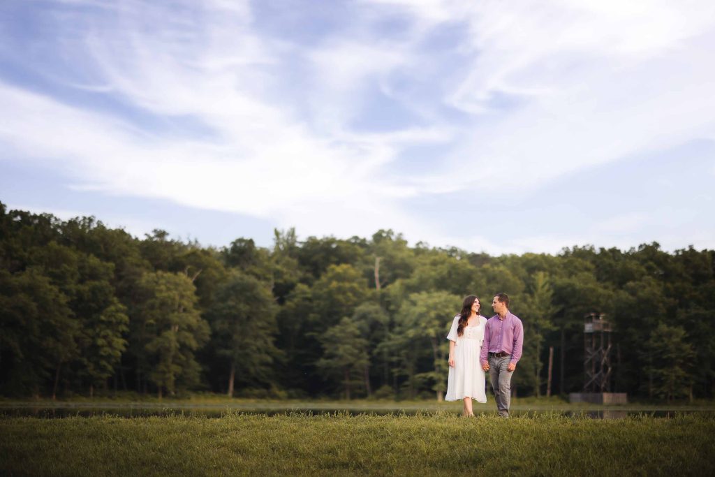 A Maryland couple sharing a tender moment during their engagement photoshoot at sunset near a serene lake.