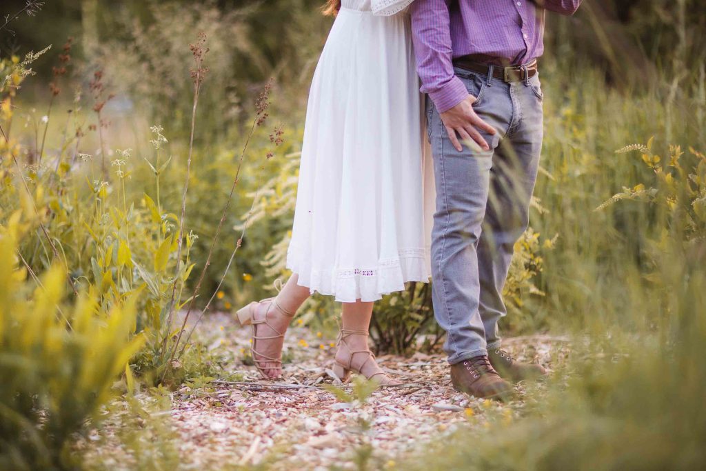 A man and woman embrace in a field of tall grass at sunset in Maryland's Patuxent Research Refuge.