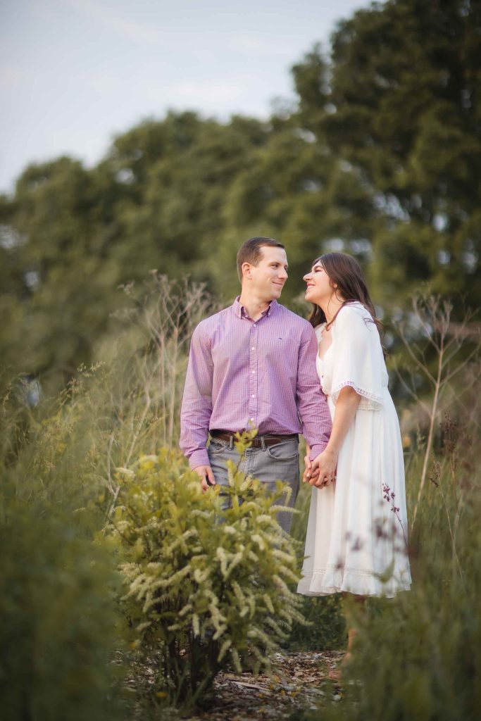 An engaged couple having their engagement photos taken in a field of tall grasses at Patuxent Research Refuge in Maryland.