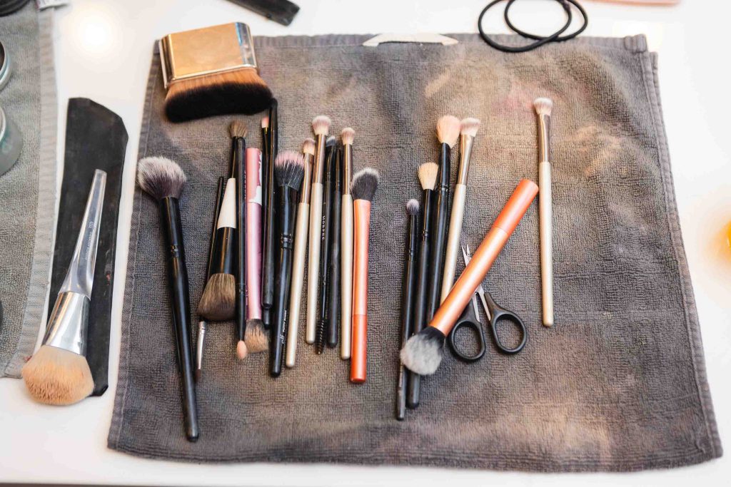 A wedding accessory essential, this set of makeup brushes is delicately placed on a sleek grey cloth atop a table, showcasing intricate details.