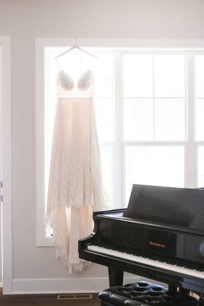 In a room, a wedding dress delicately hangs on a piano, showcasing its intricate details.