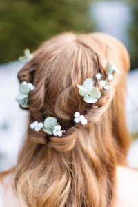 Wedding details featuring eucalyptus leaves in a bride's hair.