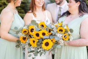 As part of the wedding details, a bride and her bridesmaids are clutching beautiful sunflower bouquets.