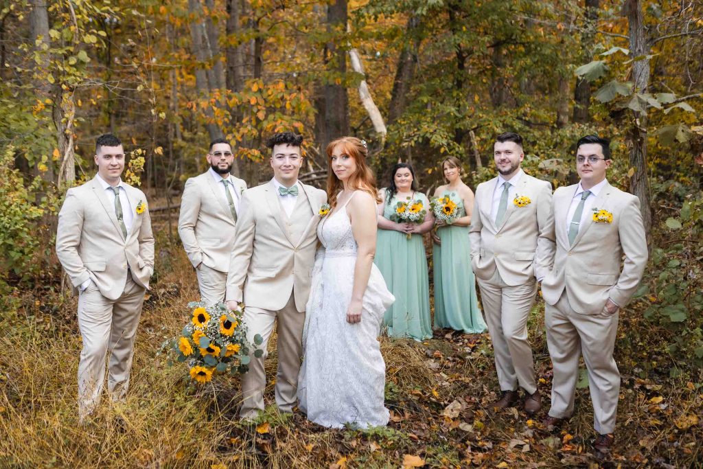 A group of bridesmaids and groomsmen standing in the woods for a portrait at a wedding held at Blackwall Barn & Lodge.