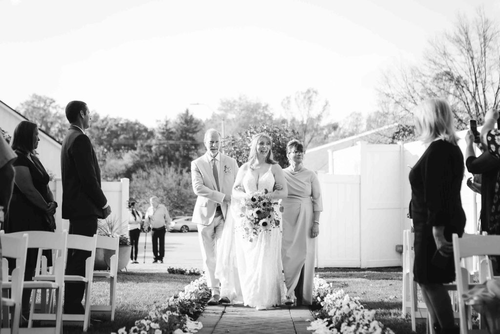 A black and white photo capturing the ceremony of a wedding as the bride and groom gracefully walk down the aisle at Blackwall Barn & Lodge.