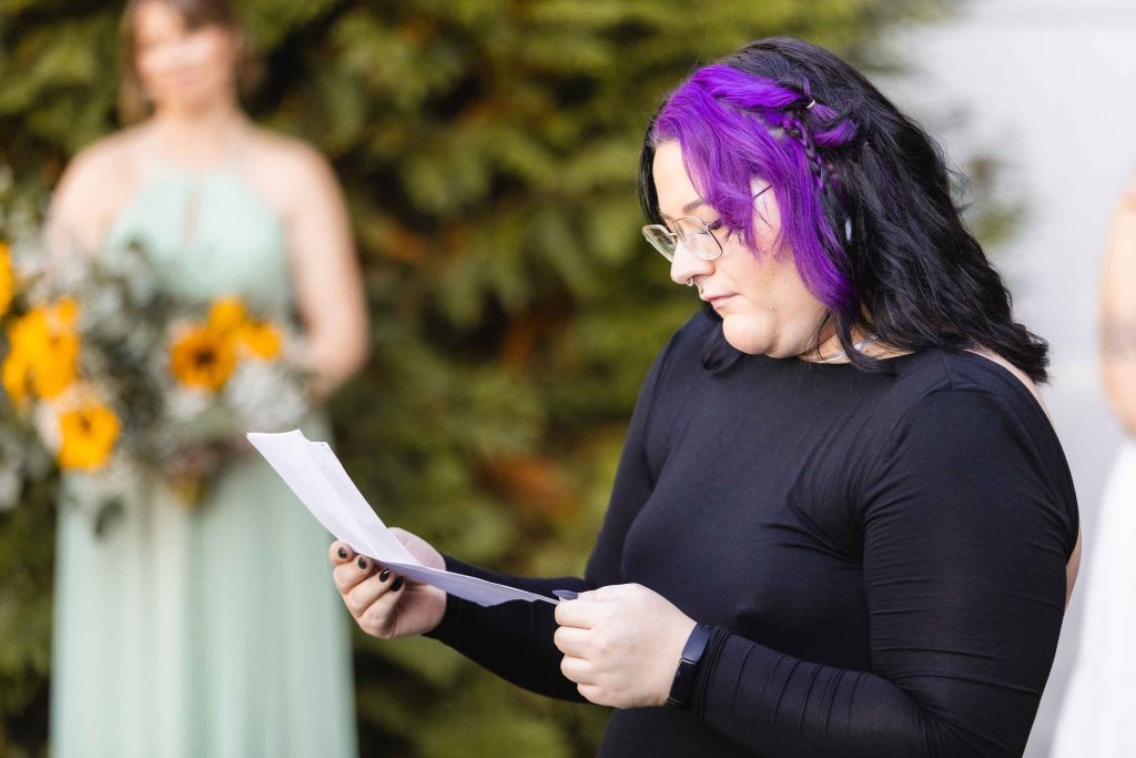 A woman with purple hair reading a letter to her bridesmaids at the Blackwall Barn & Lodge, preparing for her wedding ceremony.