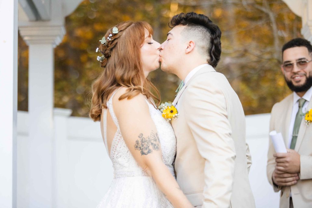 The wedding ceremony takes place at Blackwall Barn & Lodge, where the bride and groom share a tender kiss in front of a gazebo.