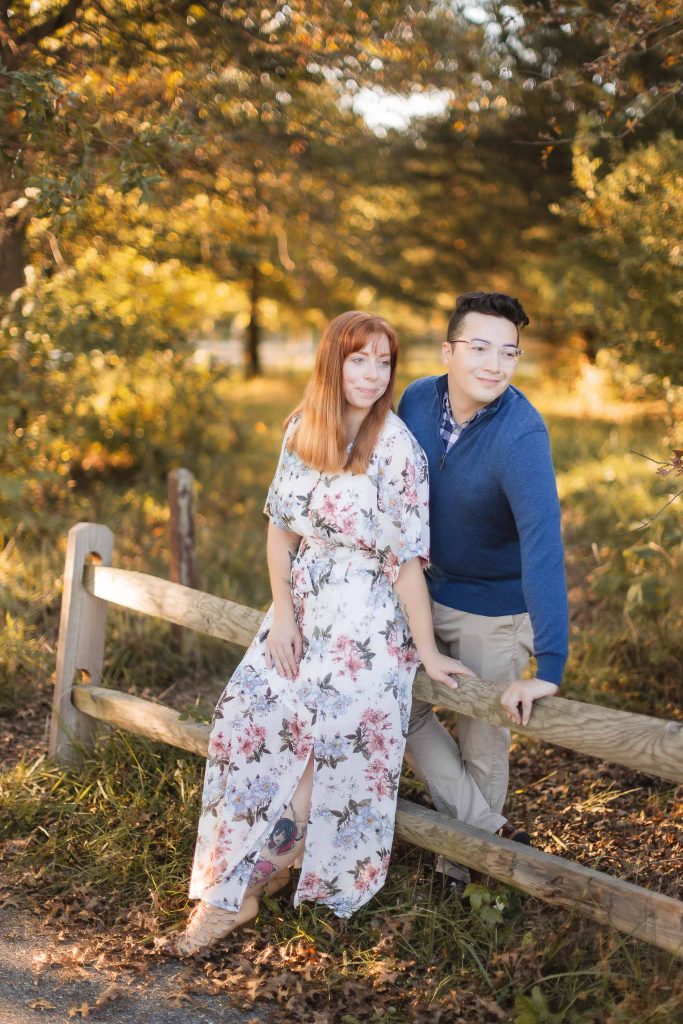 An engaged couple posing on a wooden bench in Patuxent Research Refuge, capturing beautiful portraits amidst the wooded area.