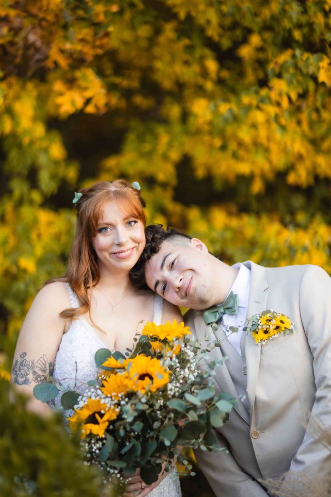 A Wedding portrait of a bride and groom posing for a photo with sunflowers at the Blackwall Barn & Lodge.