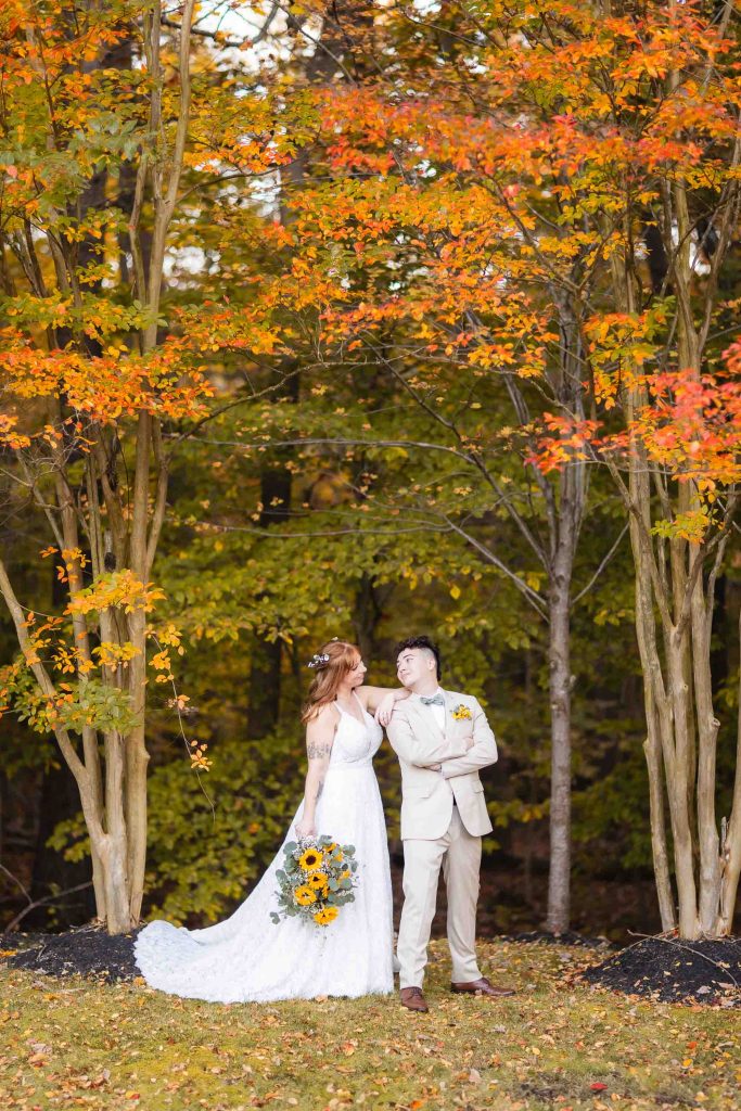 A bride and groom posing in front of fall colored trees during their wedding portrait session at Blackwall Barn & Lodge.