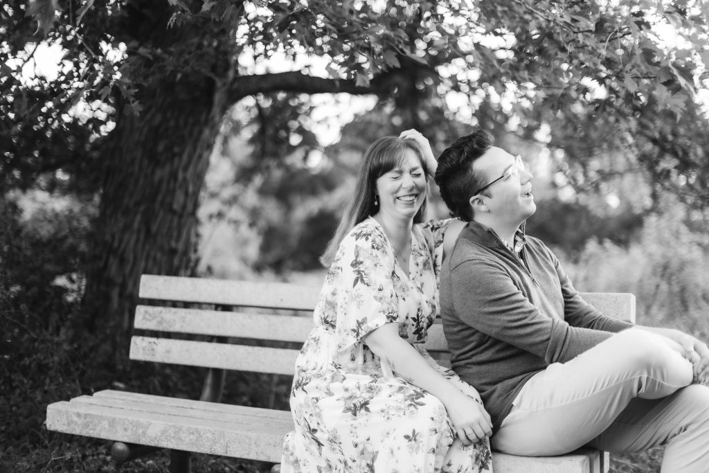 A black and white engagement photo of a couple sitting on a bench at Patuxent Research Refuge, captured beautifully for their portraits.