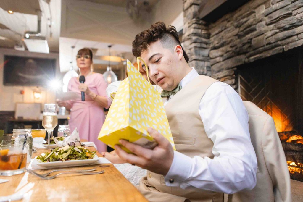 A man opens a wedding gift at Blackwall Barn & Lodge during the reception.