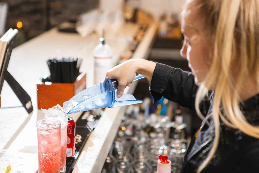 A bartender pouring a drink at a wedding reception at Blackwall Barn & Lodge.