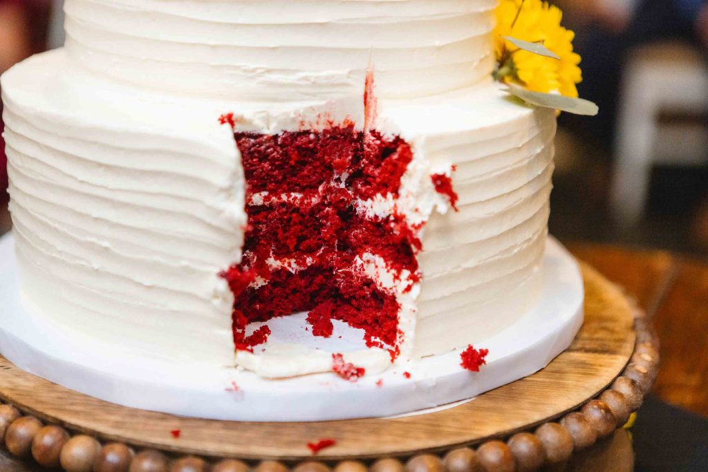 A detailed wedding cake with a slice of red velvet cake.