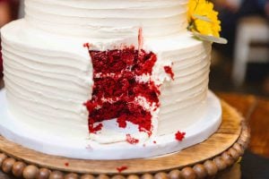 A detailed wedding cake with a slice of red velvet cake.