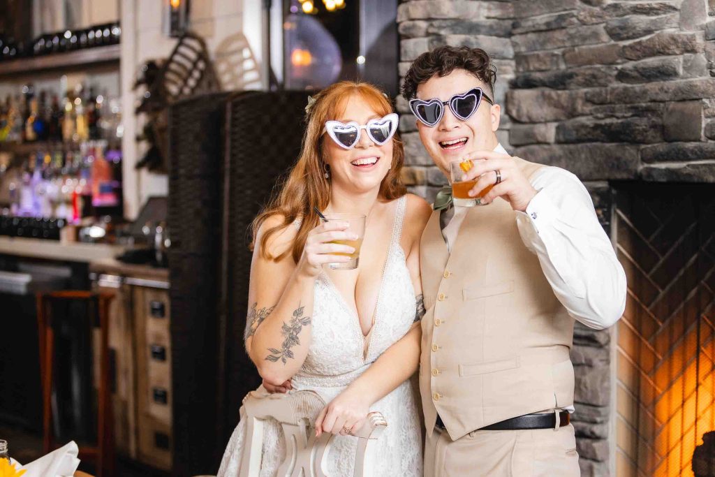 A wedding bride and groom wearing sunglasses have a reception in front of a fireplace at Blackwall Barn & Lodge.