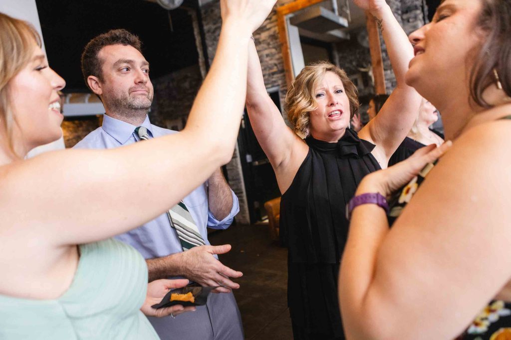 A group of people raising their hands in the air at a wedding reception at Blackwall Barn & Lodge.