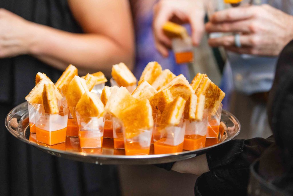 At a wedding, a group of people are skillfully holding trays of beautifully presented appetizers, paying close attention to every detail.