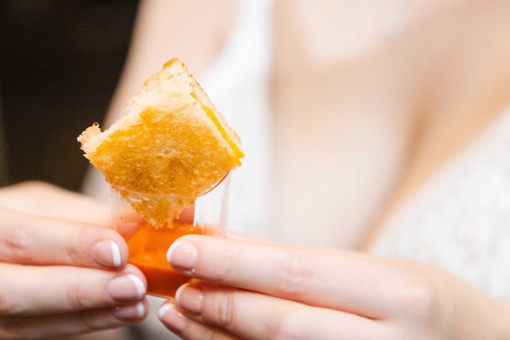 On her wedding day, a bride delicately holds a piece of bread in her hand, adding an unexpected and charming detail to her ensemble.