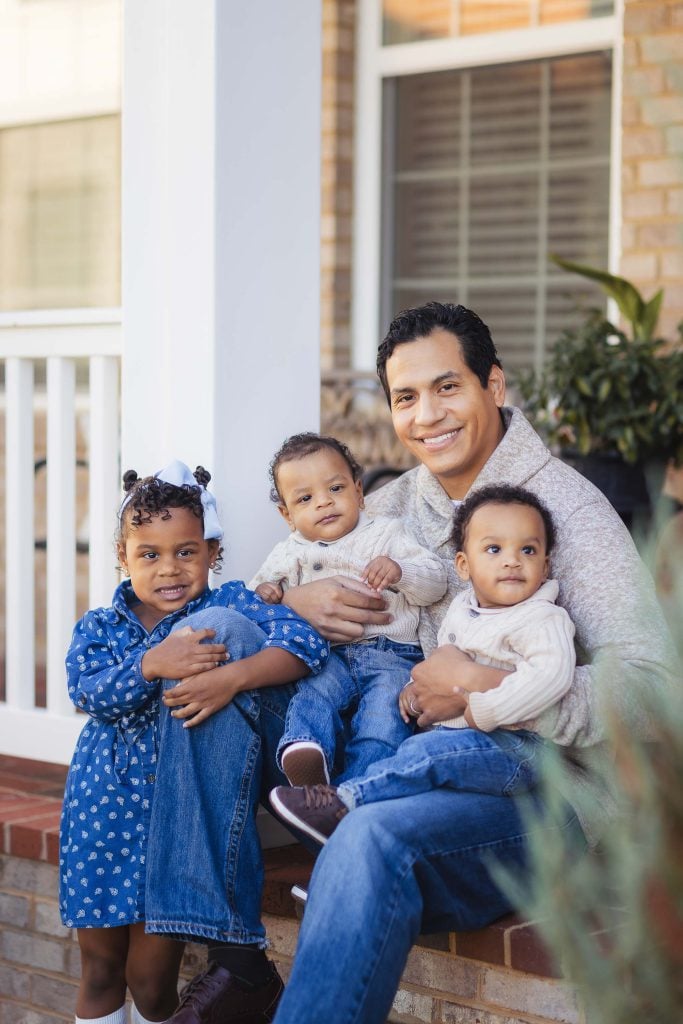 A family sitting on the steps of their home.