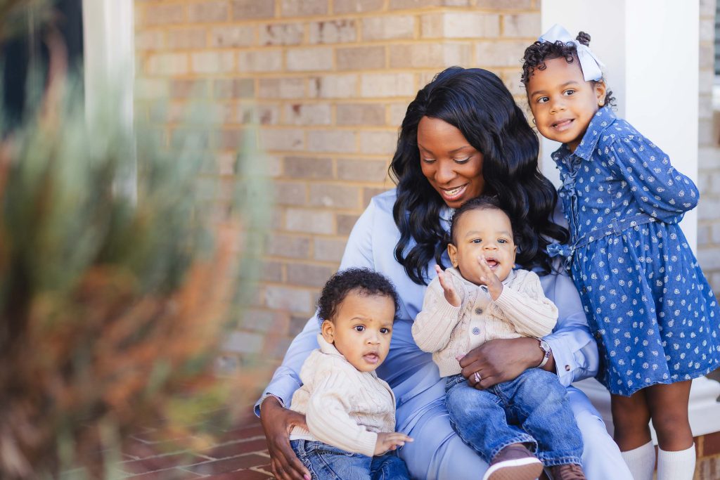A family is sitting at home on the steps of their house for a portrait session.