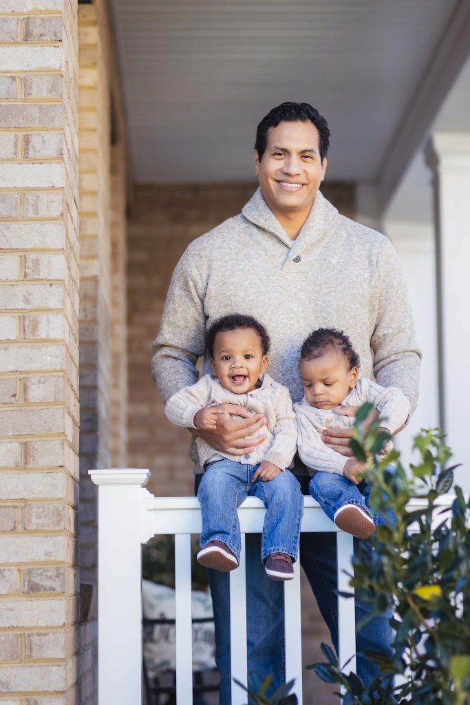A man holding two small children at home.