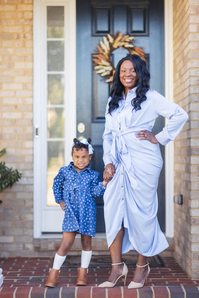 A woman and her daughter posing for a family portrait at home.