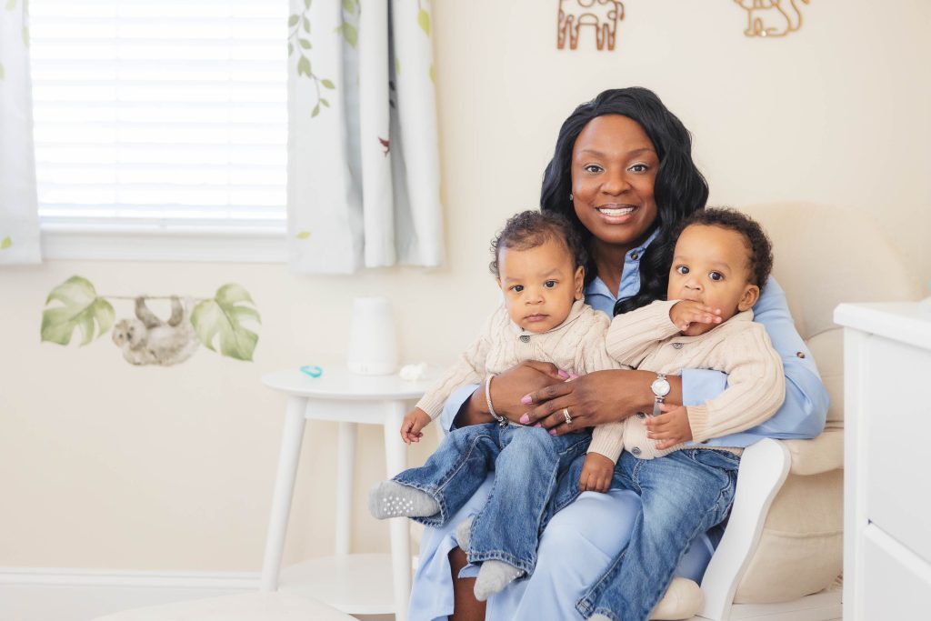 A family portrait of a woman with two children in their cozy nursery at home.