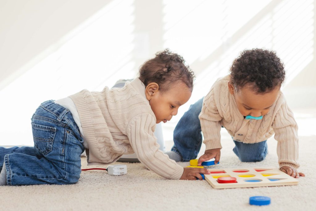 Two toddlers playing with a toy at home.