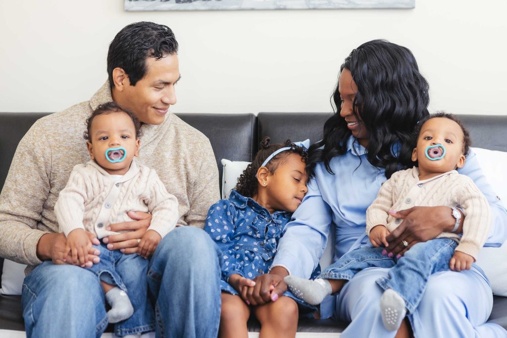 A family sits on a couch at home with their children, capturing timeless portraits together.