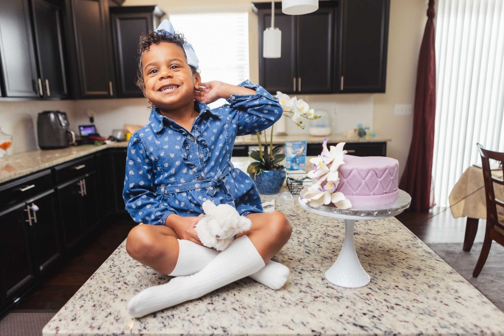 A little girl sitting on top of a kitchen counter at home.