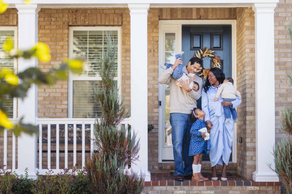 A family at home, standing on the front porch for their portraits.