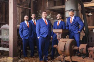 A group of groomsmen in blue suits standing in a barn.