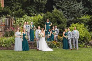 A group of bridesmaids and groomsmen pose for a photo in a garden.
